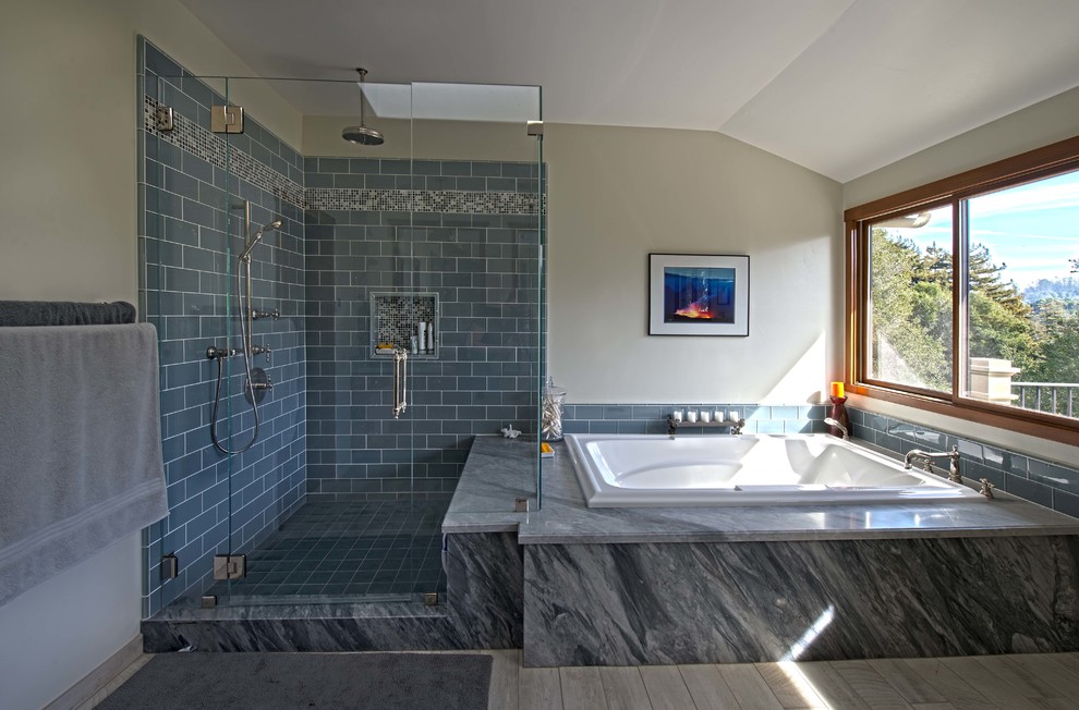 На фото: большая главная ванная комната в стиле кантри с фасадами в стиле шейкер, темными деревянными фасадами, угловым душем, унитазом-моноблоком, синей плиткой, стеклянной плиткой, белыми стенами, полом из травертина, врезной раковиной, столешницей из гранита, накладной ванной, серым полом, душем с распашными дверями и синей столешницей