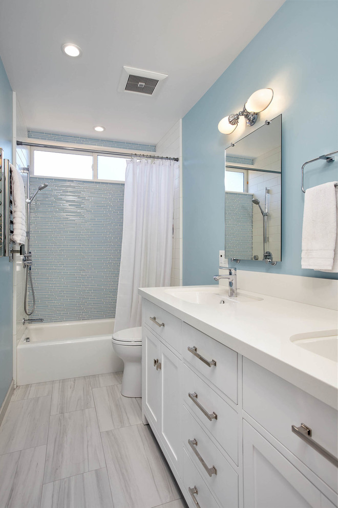 Cette image montre une salle de bain traditionnelle de taille moyenne avec un placard à porte shaker, des portes de placard blanches, une baignoire en alcôve, un combiné douche/baignoire, WC séparés, un carrelage bleu, un carrelage en pâte de verre, un mur bleu, un sol en carrelage de porcelaine, un lavabo encastré, un plan de toilette en quartz modifié, un sol gris et une cabine de douche avec un rideau.