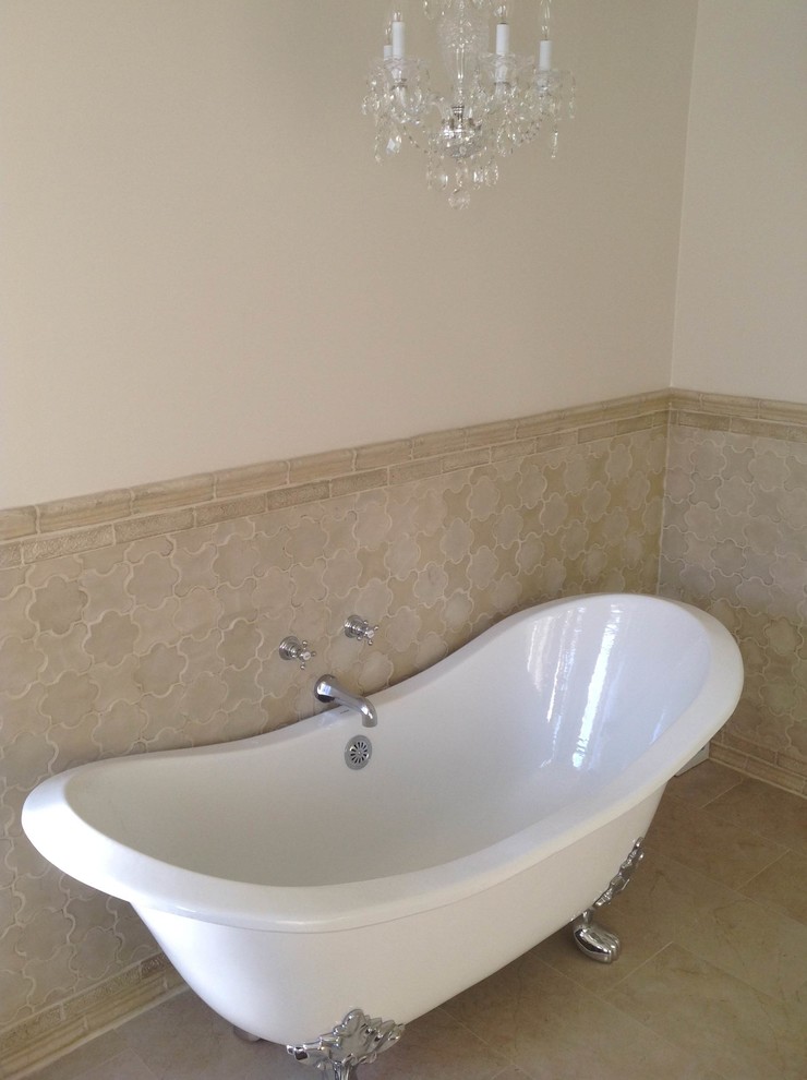 Modern inredning av ett badrum, med ett badkar med tassar, vit kakel och cementkakel