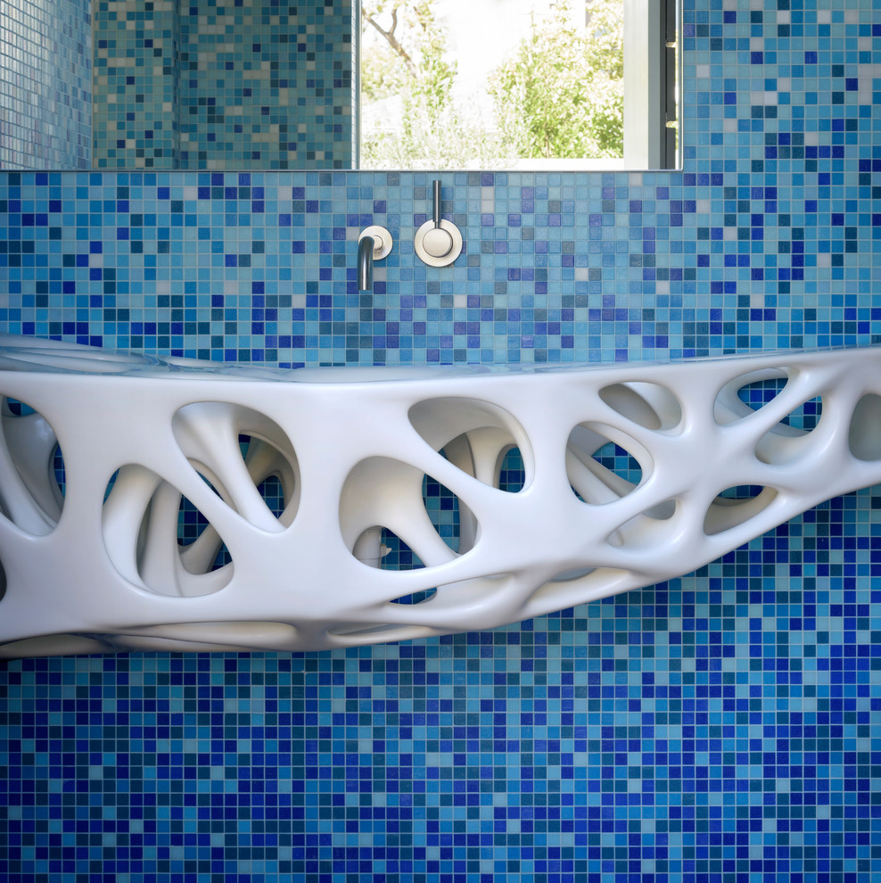 Inredning av ett modernt grå grått en-suite badrum, med blå kakel, mosaik, blå väggar, ett väggmonterat handfat, skåp i shakerstil, skåp i mellenmörkt trä, ett fristående badkar, en kantlös dusch, mellanmörkt trägolv, bänkskiva i betong, brunt golv och dusch med gångjärnsdörr