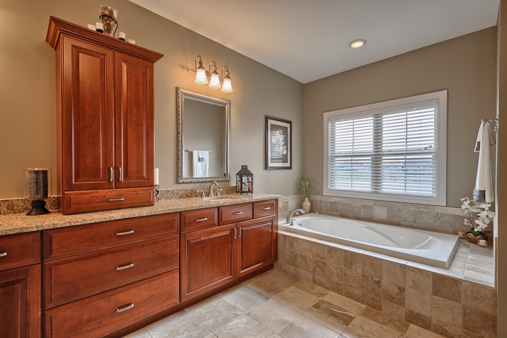 Inspiration for a mid-sized timeless master beige tile, white tile and stone slab ceramic tile bathroom remodel in St Louis with raised-panel cabinets, medium tone wood cabinets, a one-piece toilet, beige walls, a drop-in sink and solid surface countertops