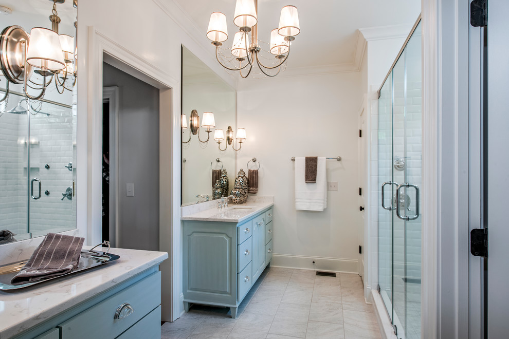 This is an example of a large traditional ensuite bathroom in Other with a submerged sink, flat-panel cabinets, blue cabinets, a double shower, white tiles, porcelain tiles, white walls, a two-piece toilet, marble flooring and marble worktops.