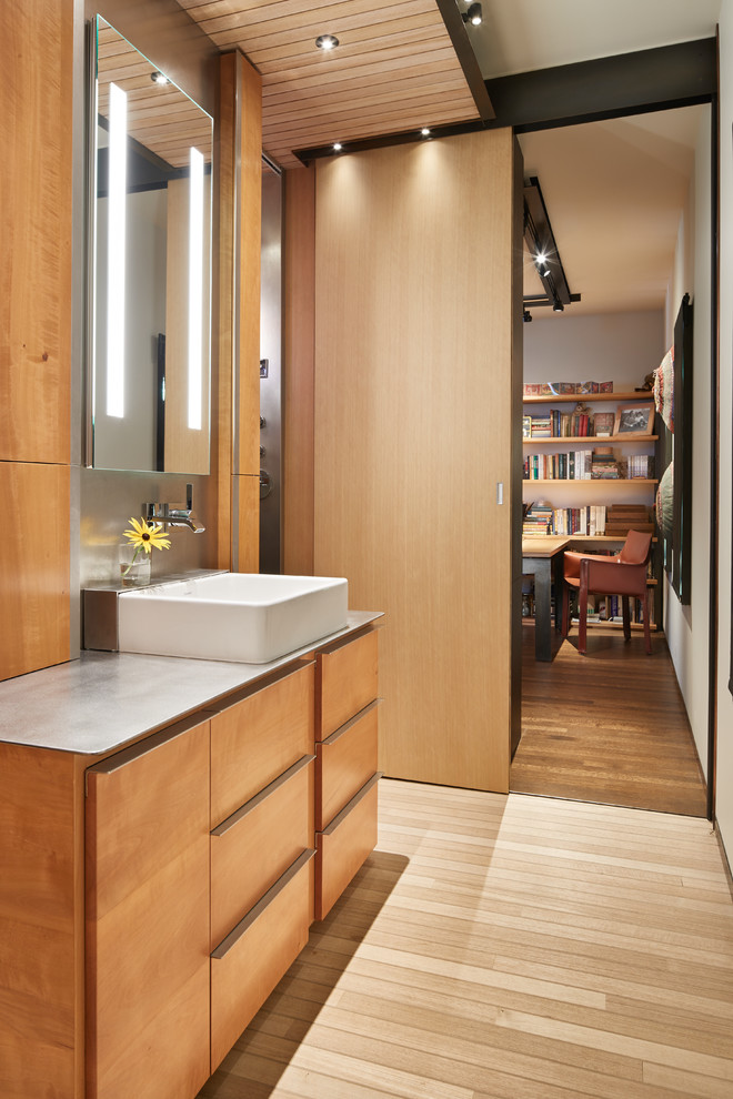 Réalisation d'une salle de bain principale design en bois brun avec un plan de toilette en acier inoxydable, un placard à porte plane, parquet clair, un lavabo posé et un sol beige.