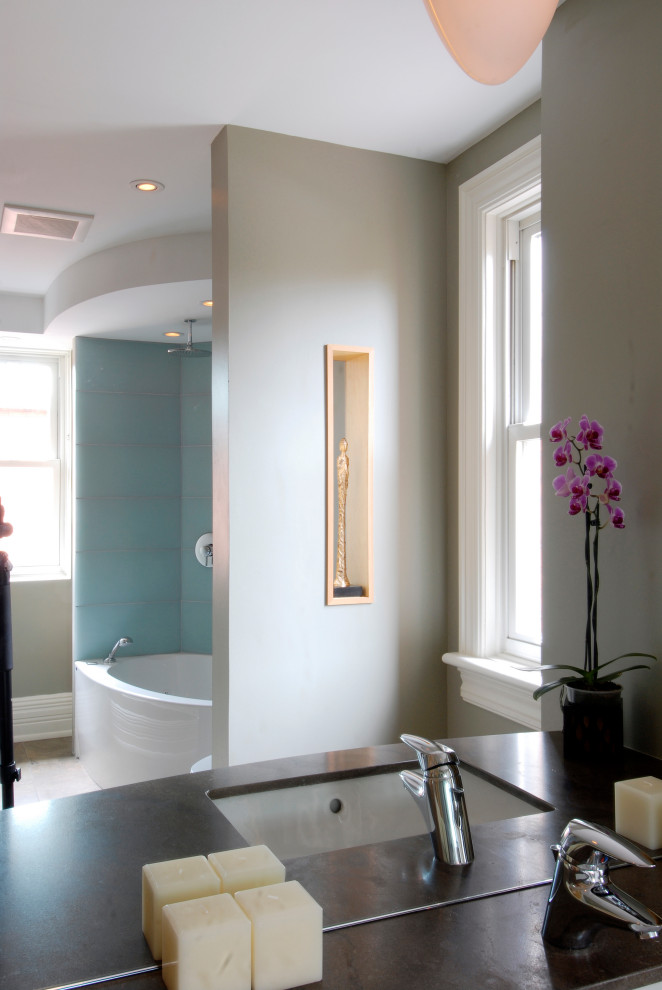Modern inredning av ett mellanstort brun brunt badrum, med öppna hyllor, skåp i mellenmörkt trä, ett hörnbadkar, en toalettstol med hel cisternkåpa, grå väggar, klinkergolv i porslin, ett undermonterad handfat, bänkskiva i akrylsten och flerfärgat golv