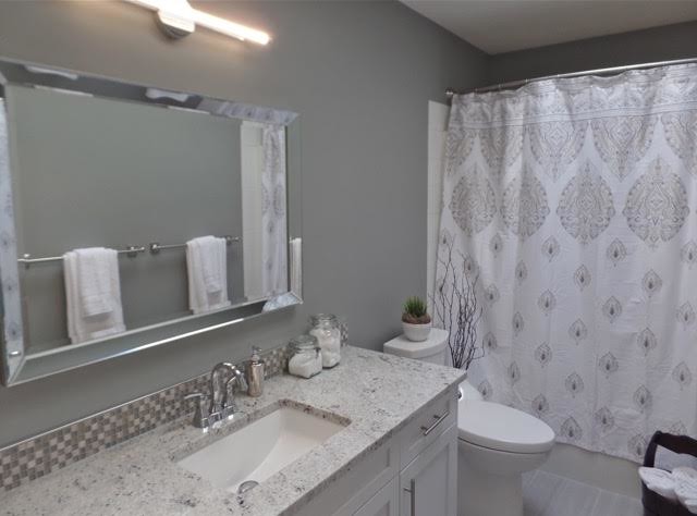 Aménagement d'une salle de bain classique de taille moyenne avec un placard à porte shaker, des portes de placard blanches, une baignoire en alcôve, un combiné douche/baignoire, WC séparés, un carrelage gris, un carrelage blanc, des carreaux de céramique, un mur gris, un lavabo encastré et un plan de toilette en granite.