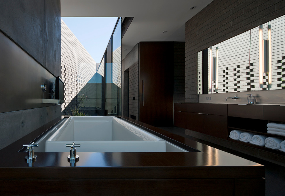 Cette image montre une grande salle de bain principale minimaliste en bois brun avec un placard à porte plane, une baignoire posée, une douche ouverte, un carrelage bleu et un mur gris.