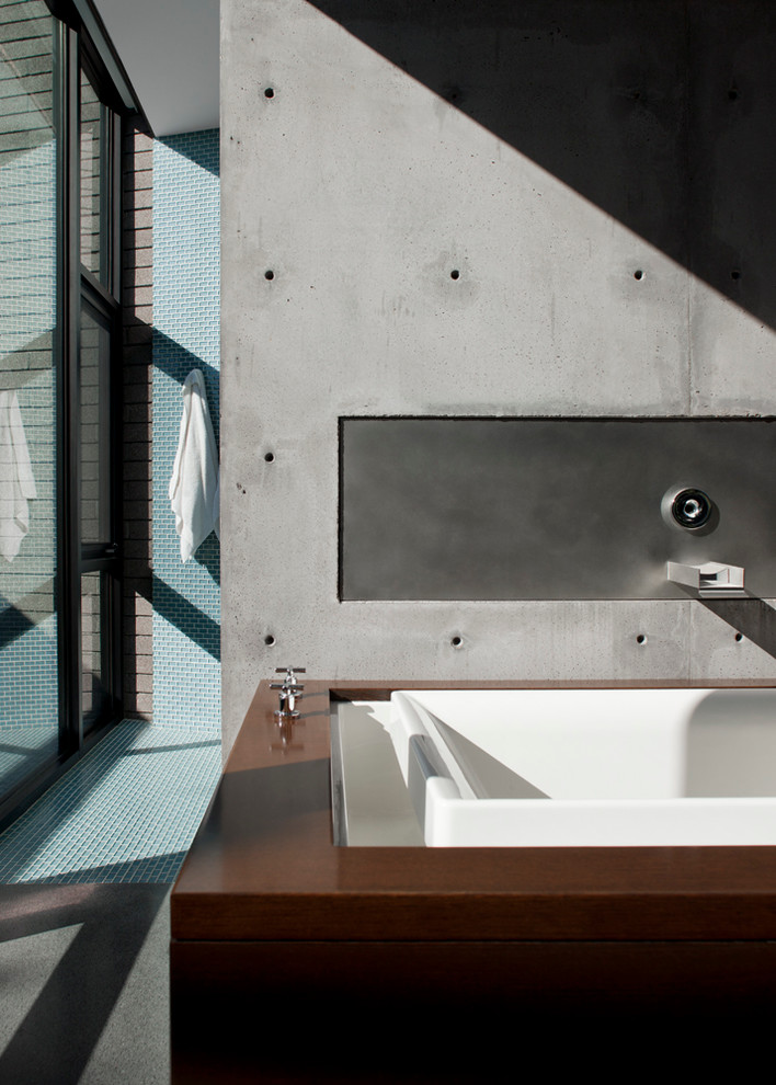 Exemple d'une grande salle de bain principale moderne en bois brun avec un placard à porte plane, une baignoire posée, une douche ouverte, un carrelage bleu, des plaques de verre et un mur gris.