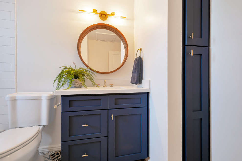Пример оригинального дизайна: детская ванная комната среднего размера в стиле кантри с фасадами в стиле шейкер, синими фасадами, ванной в нише, душем над ванной, раздельным унитазом, белой плиткой, керамической плиткой, белыми стенами, полом из керамогранита, врезной раковиной, столешницей из искусственного кварца, синим полом, шторкой для ванной, белой столешницей, тумбой под одну раковину и встроенной тумбой
