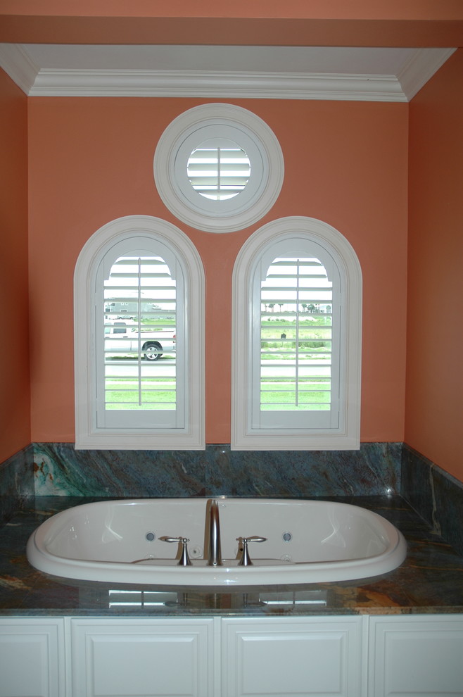 オーランドにある高級な中くらいなトランジショナルスタイルのおしゃれなマスターバスルーム (レイズドパネル扉のキャビネット、白いキャビネット、ドロップイン型浴槽、緑のタイル、大理石タイル、オレンジの壁、大理石の洗面台) の写真