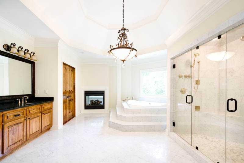 На фото: огромная главная ванная комната в средиземноморском стиле с фасадами цвета дерева среднего тона, накладной ванной, двойным душем и белыми стенами с