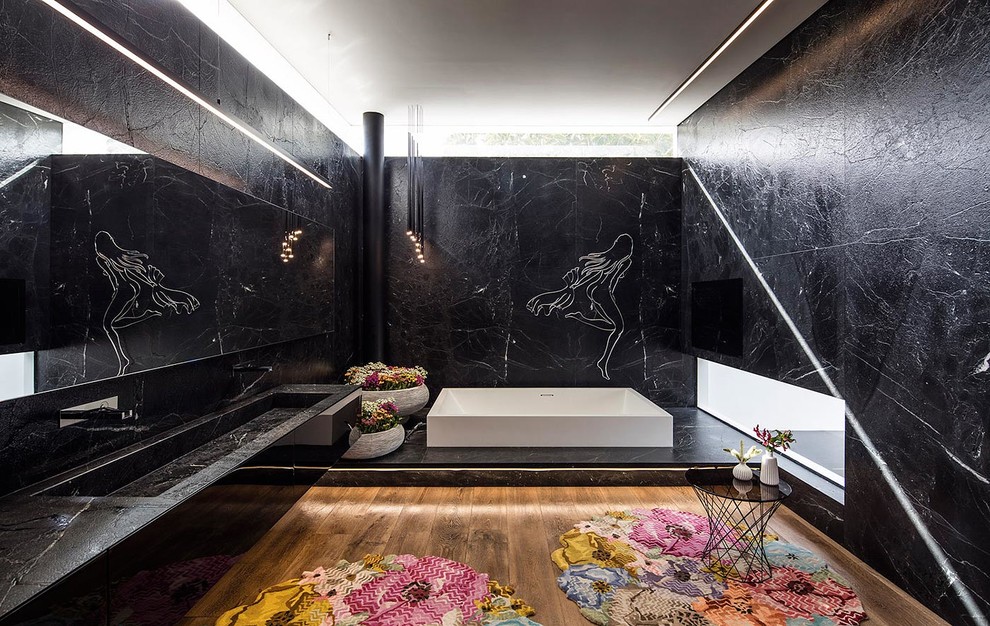 Exempel på ett stort modernt en-suite badrum, med svarta skåp, ett undermonterat badkar, svart kakel, stenkakel, svarta väggar, mellanmörkt trägolv, ett väggmonterat handfat, granitbänkskiva, luckor med infälld panel, en öppen dusch och en vägghängd toalettstol