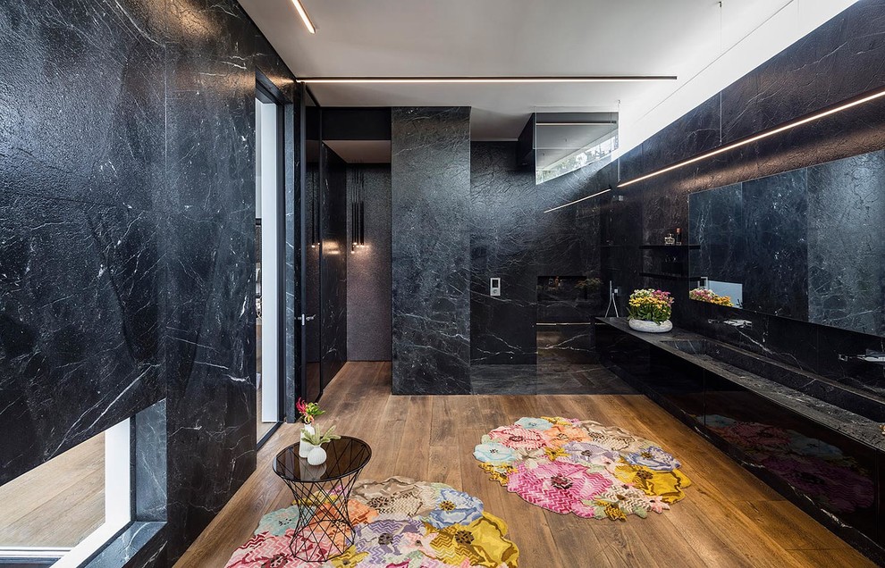 Inredning av ett modernt stort en-suite badrum, med släta luckor, svarta skåp, svart kakel, stenkakel, mellanmörkt trägolv, granitbänkskiva, en kantlös dusch och ett avlångt handfat