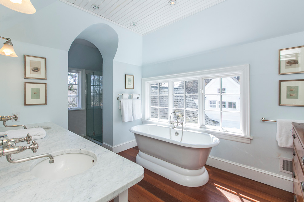 Mittelgroßes Klassisches Badezimmer mit Unterbauwaschbecken, freistehender Badewanne, blauer Wandfarbe und dunklem Holzboden in New York