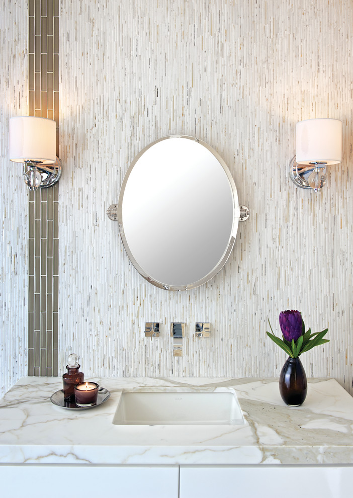 Inredning av ett modernt badrum, med ett undermonterad handfat, vita skåp, marmorbänkskiva, stickkakel, vita väggar och vit kakel