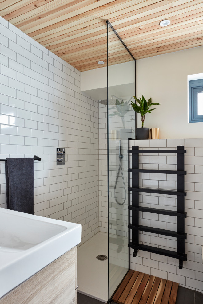 Bild på ett litet badrum med dusch, med ett platsbyggt badkar, en hörndusch, en toalettstol med hel cisternkåpa, vit kakel, keramikplattor, vita väggar, skiffergolv, ett avlångt handfat, grått golv och med dusch som är öppen