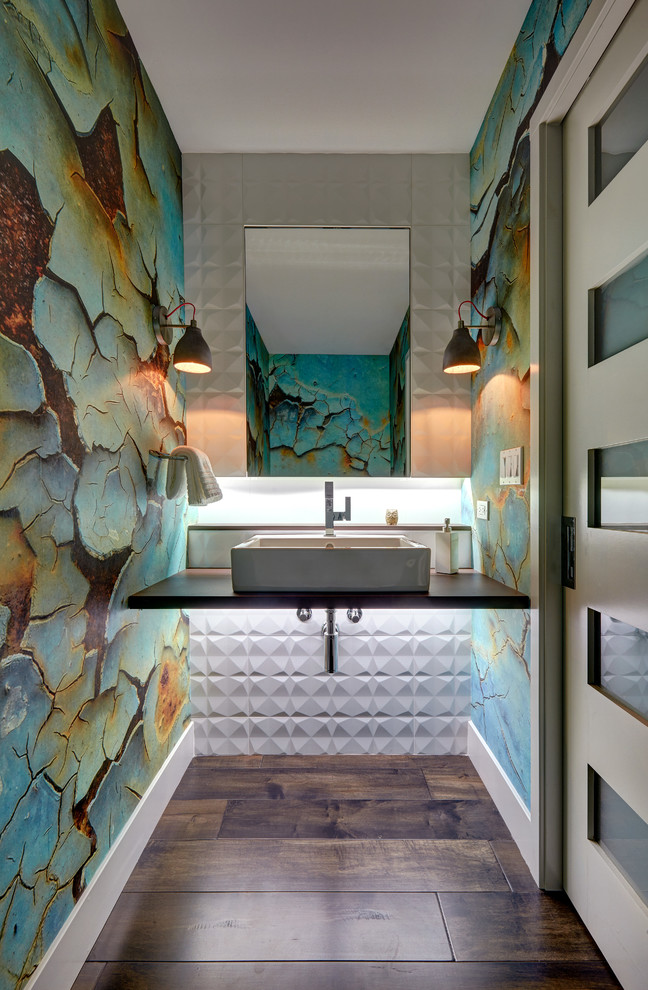 Cette photo montre une petite salle de bain tendance avec WC suspendus, un carrelage blanc, des carreaux de porcelaine, un mur multicolore, un sol en bois brun, une vasque et un plan de toilette en quartz modifié.