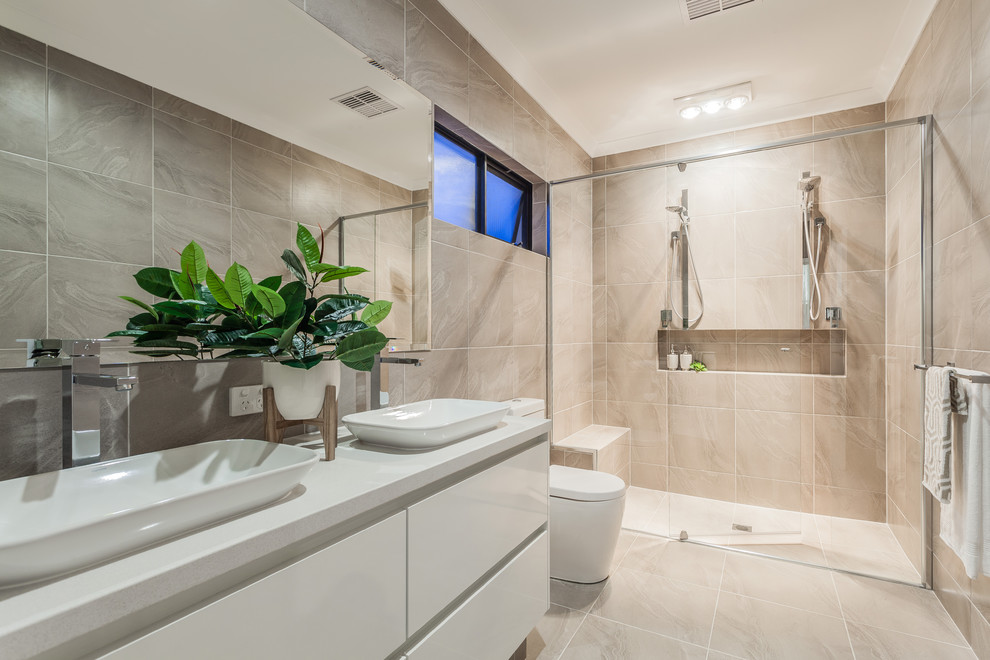 Modernes Duschbad mit flächenbündigen Schrankfronten, weißen Schränken, bodengleicher Dusche, beigen Fliesen, beiger Wandfarbe, Aufsatzwaschbecken, beigem Boden, Schiebetür-Duschabtrennung und weißer Waschtischplatte in Perth
