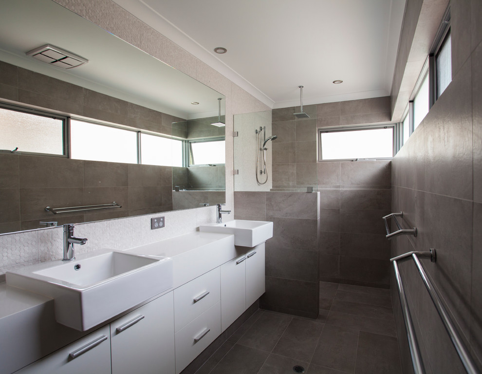 Inredning av ett modernt en-suite badrum, med släta luckor, vita skåp, ett hörnbadkar, en hörndusch, brun kakel, mosaik, bruna väggar, ett avlångt handfat, bänkskiva i akrylsten, brunt golv och med dusch som är öppen