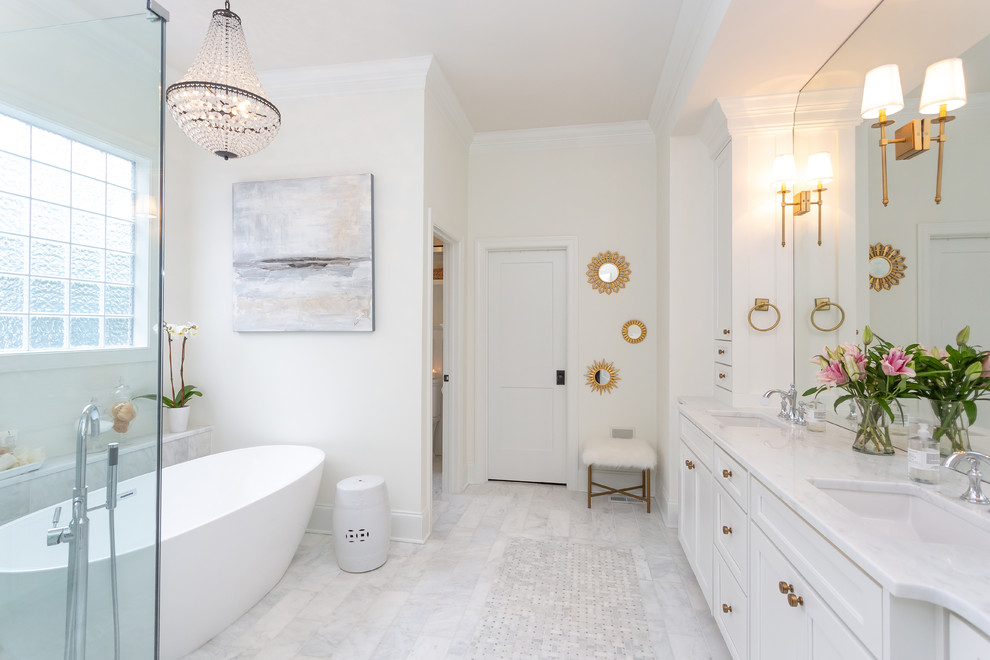 Inredning av ett klassiskt vit vitt badrum, med luckor med infälld panel, vita skåp, ett fristående badkar, vita väggar, ett undermonterad handfat och vitt golv