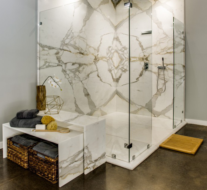 Klassisk inredning av ett en-suite badrum, med grå väggar, betonggolv, ett väggmonterat handfat, marmorbänkskiva, en kantlös dusch och en toalettstol med hel cisternkåpa