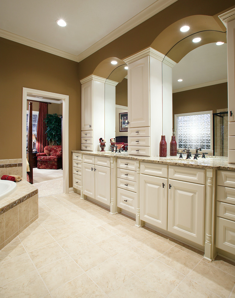 Large traditional bathroom in Indianapolis with raised-panel cabinets, white cabinets, a built-in bath, a corner shower, ceramic tiles, beige walls, ceramic flooring, a submerged sink and granite worktops.