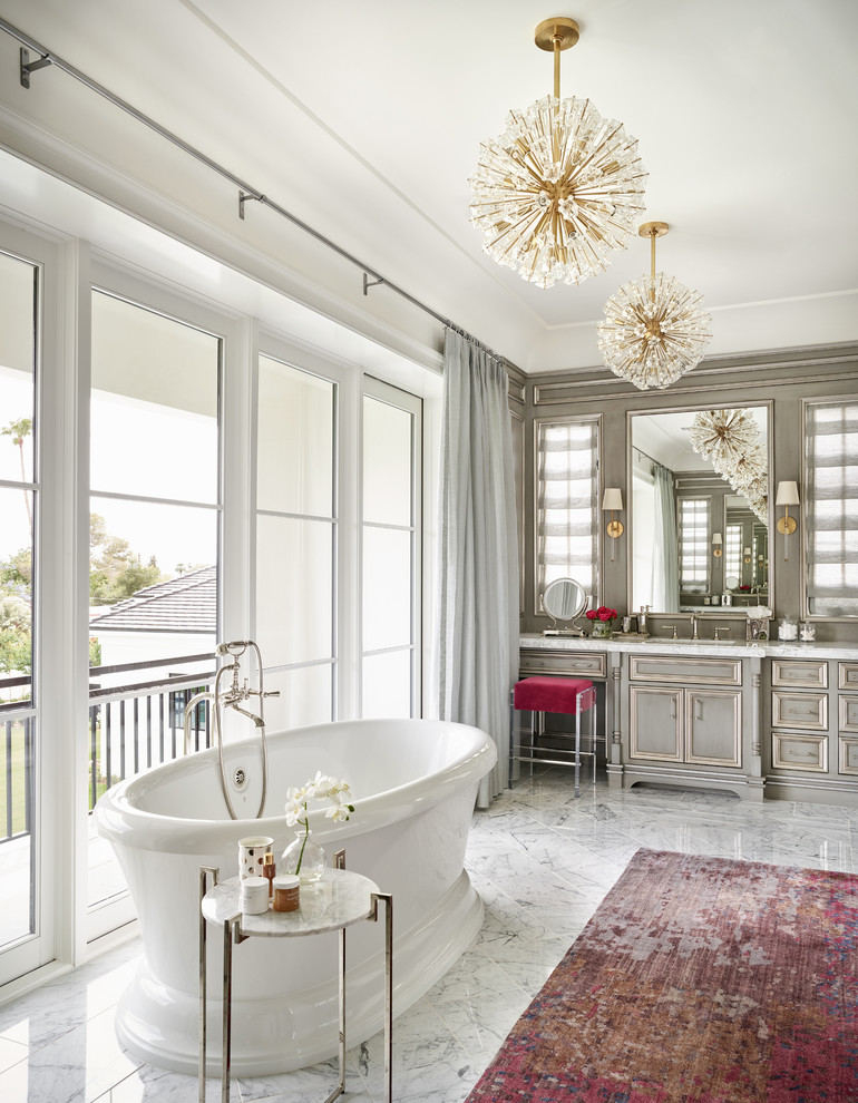Источник вдохновения для домашнего уюта: главная ванная комната в классическом стиле с серыми фасадами, отдельно стоящей ванной, белой столешницей, зеркалом с подсветкой и фасадами с утопленной филенкой