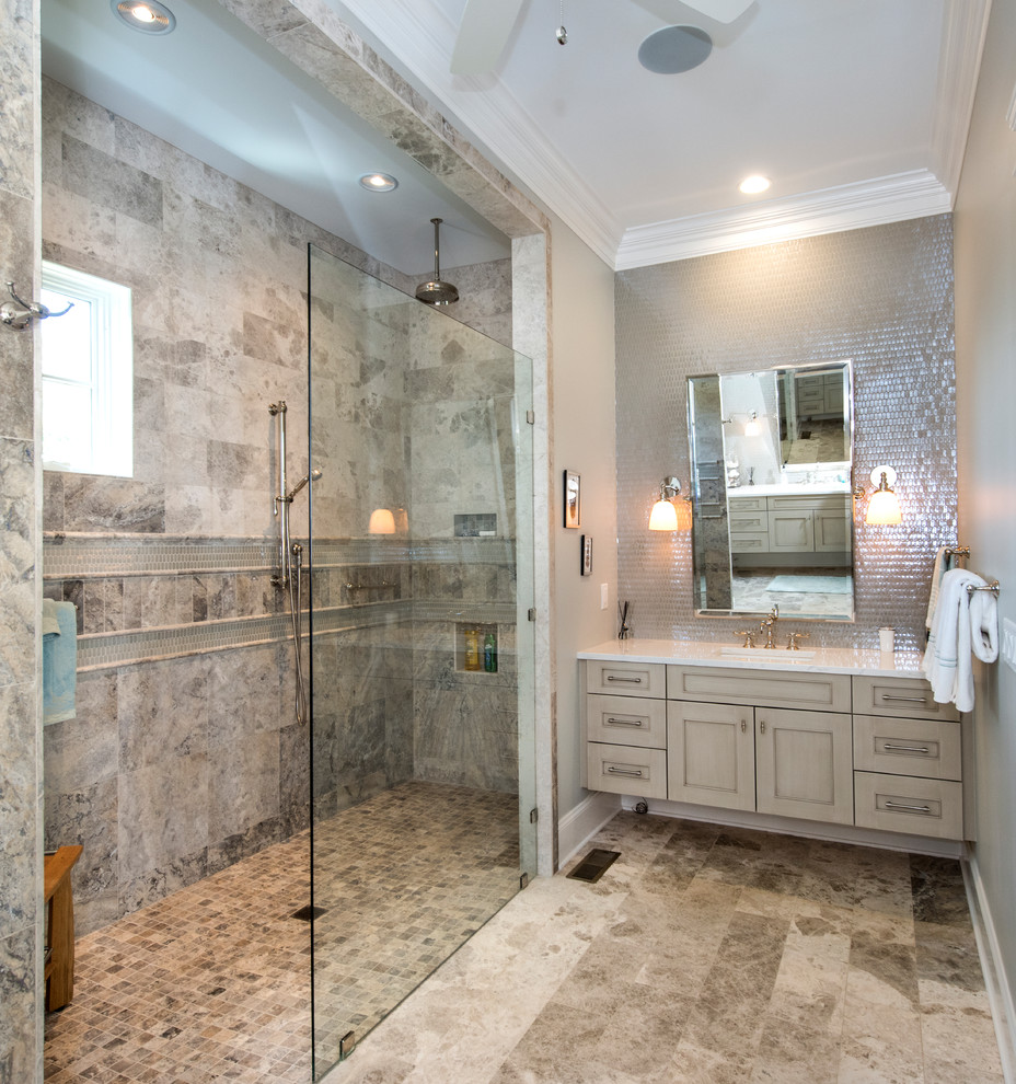 Photo of a large coastal ensuite bathroom in Nashville with recessed-panel cabinets, grey cabinets, a built-in shower, a one-piece toilet, grey tiles, travertine tiles, grey walls, travertine flooring, a submerged sink, engineered stone worktops, grey floors and an open shower.