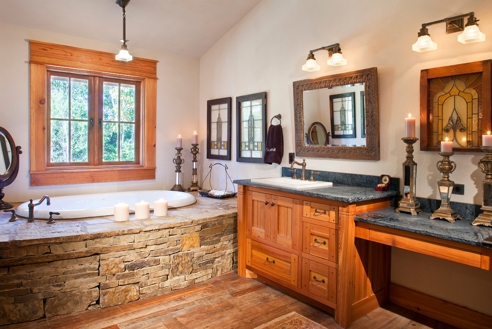 Diseño de cuarto de baño rural con lavabo encastrado, armarios con paneles empotrados, puertas de armario de madera oscura y bañera encastrada