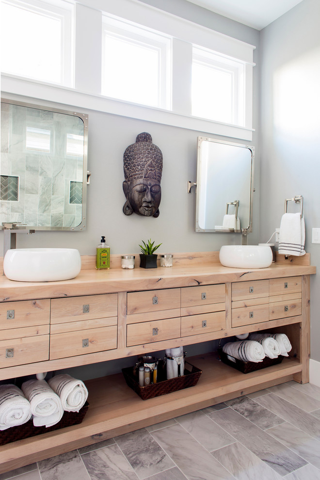 Asiatisk inredning av ett mellanstort brun brunt en-suite badrum, med grå kakel, porslinskakel, grå väggar, klinkergolv i porslin, släta luckor, skåp i ljust trä, ett fristående handfat, en öppen dusch, en toalettstol med hel cisternkåpa, träbänkskiva och grått golv