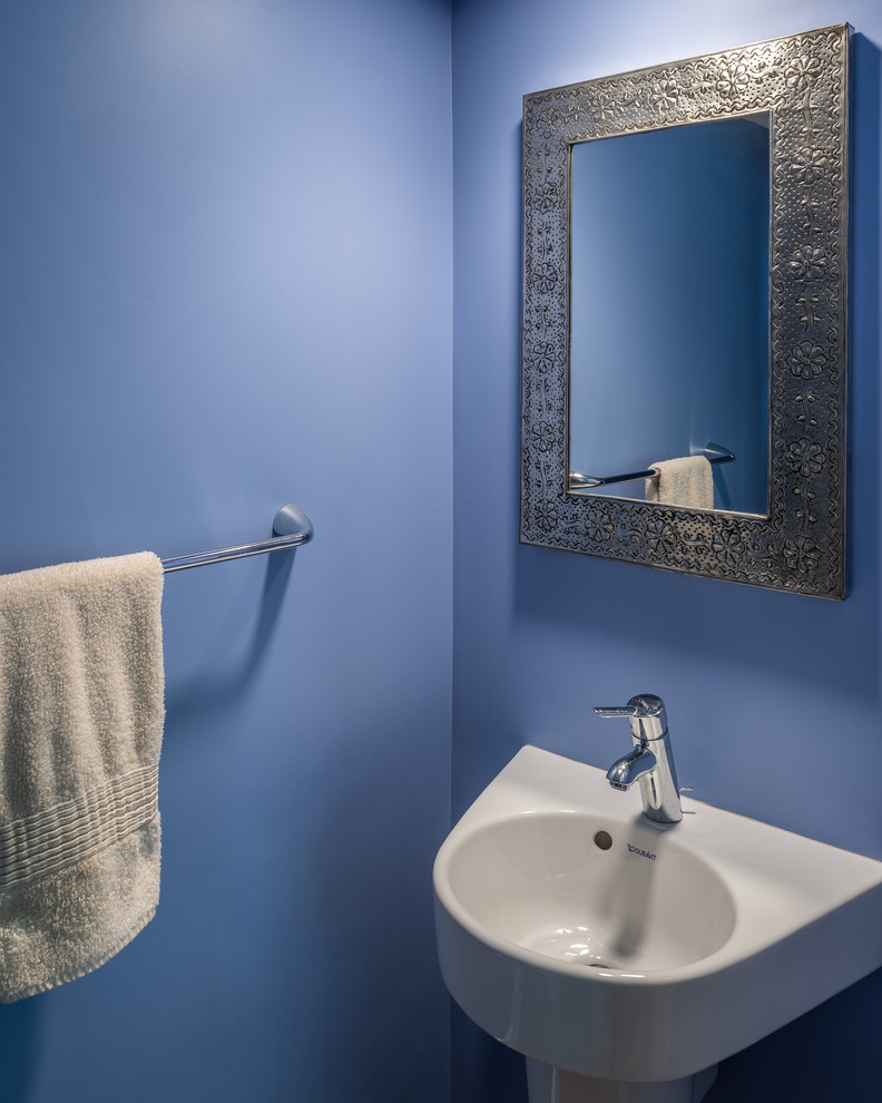 Réalisation d'une salle de bain tradition avec un mur bleu et un lavabo suspendu.