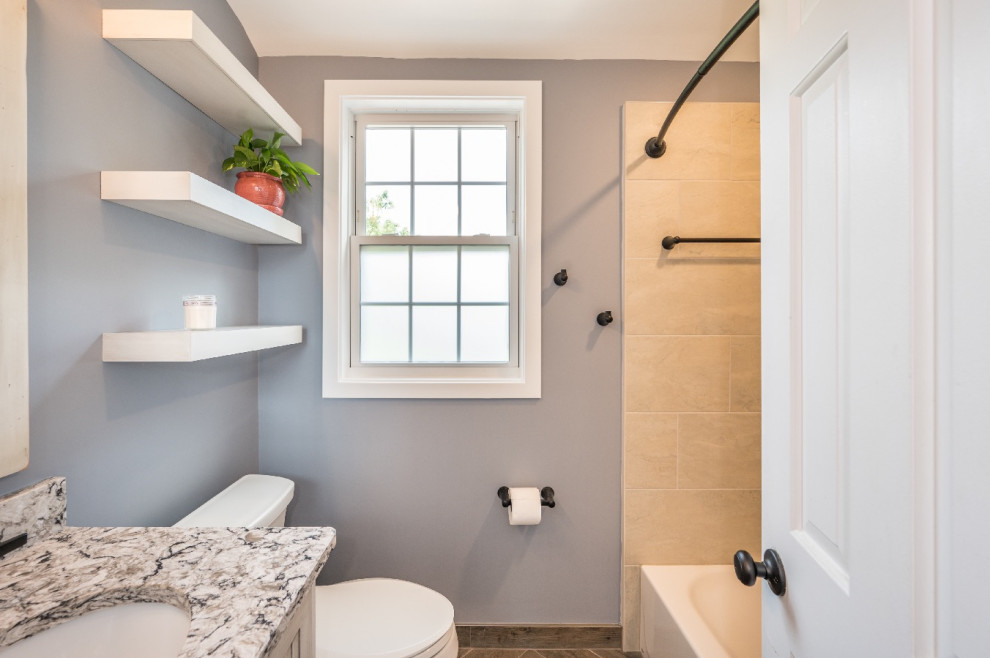 Small cottage 3/4 ceramic tile, brown floor and single-sink tub/shower combo photo in DC Metro with shaker cabinets, distressed cabinets, a two-piece toilet, gray walls, an undermount sink, granite countertops, multicolored countertops and a built-in vanity