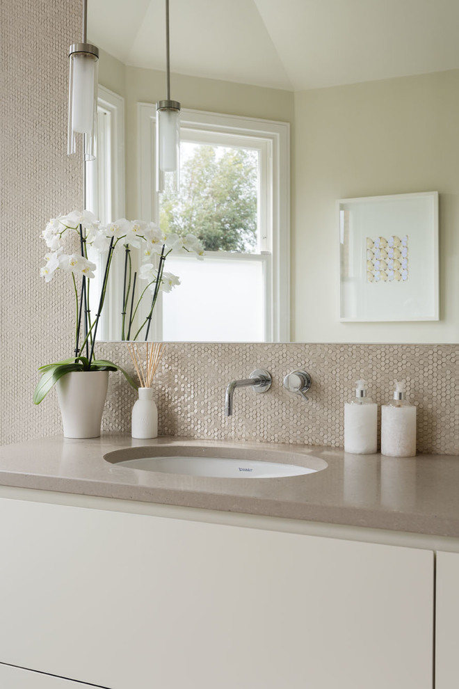 This is an example of a contemporary bathroom in London with beige tiles, beige walls and a built-in sink.
