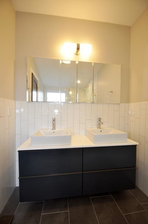 Cette photo montre une petite salle de bain principale tendance avec un carrelage blanc, des carreaux de céramique, un mur blanc, un sol en carrelage de porcelaine, une vasque, un plan de toilette en quartz modifié et un sol noir.