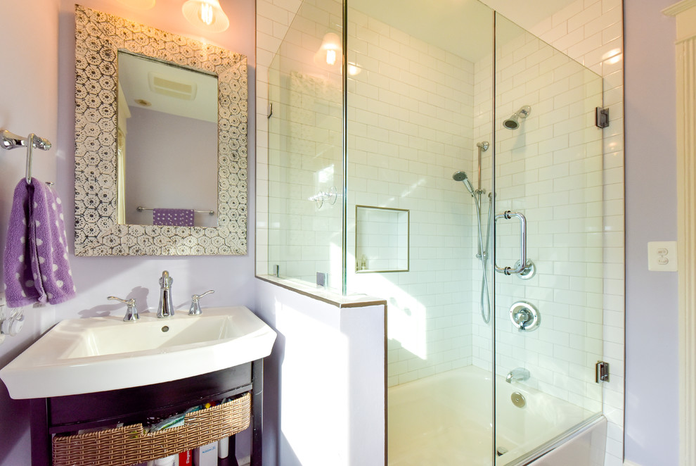 Cette image montre une salle d'eau traditionnelle en bois foncé de taille moyenne avec un placard sans porte, une baignoire en alcôve, un combiné douche/baignoire, un carrelage blanc, un carrelage métro, un mur violet, un lavabo posé et une cabine de douche à porte battante.