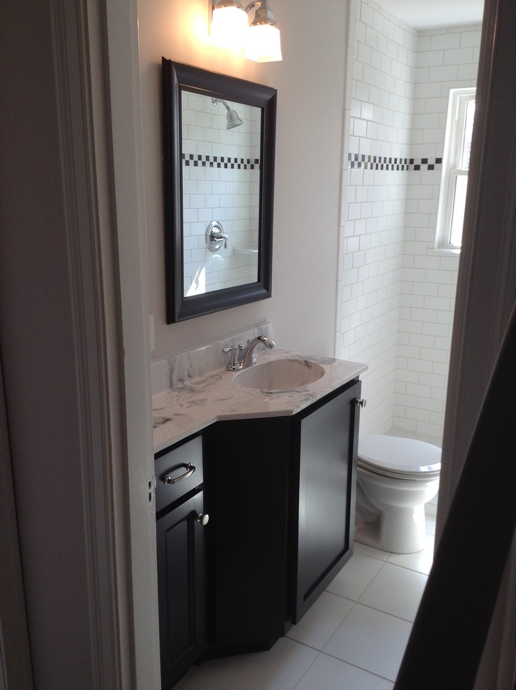Idéer för ett litet klassiskt badrum, med ett integrerad handfat, skåp i shakerstil, svarta skåp, bänkskiva i akrylsten, en dusch i en alkov, en toalettstol med separat cisternkåpa, vit kakel, keramikplattor, grå väggar och klinkergolv i keramik