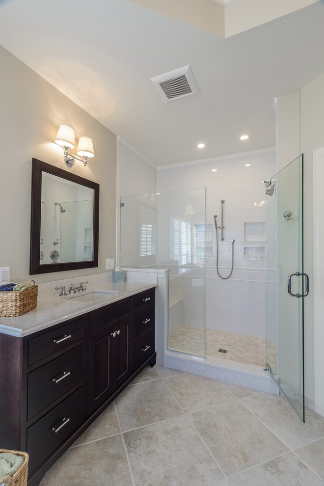 This is an example of a large traditional ensuite bathroom in DC Metro with a submerged sink, recessed-panel cabinets, dark wood cabinets, granite worktops, a freestanding bath, a corner shower, a two-piece toilet, beige tiles, ceramic tiles, beige walls and ceramic flooring.