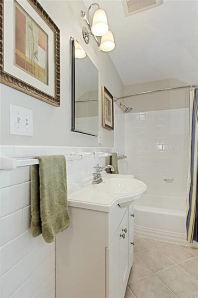 Inredning av ett klassiskt litet badrum, med luckor med upphöjd panel, vita skåp, bänkskiva i akrylsten, ett badkar i en alkov, en dusch/badkar-kombination, grå kakel och keramikplattor