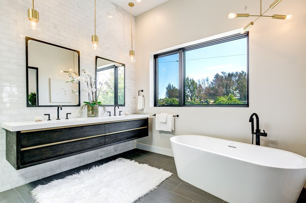 Medium sized scandi ensuite bathroom in Los Angeles with flat-panel cabinets, black cabinets, a freestanding bath, a double shower, white tiles, marble tiles, white walls, porcelain flooring, a submerged sink, solid surface worktops, grey floors and a hinged door.