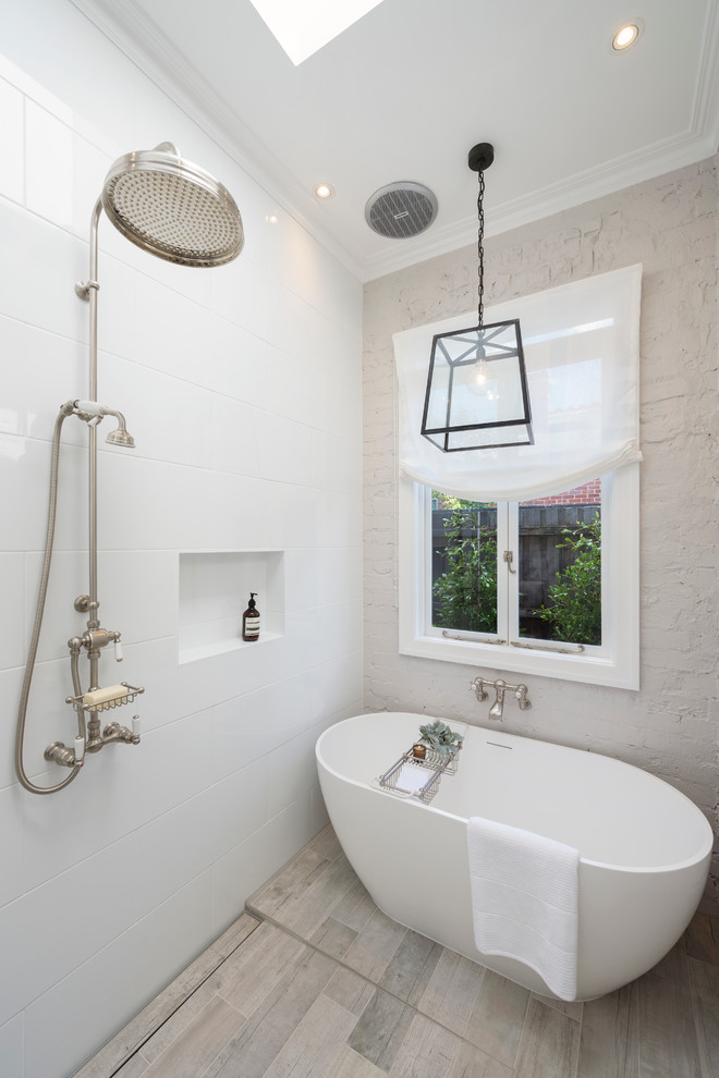 Modern inredning av ett badrum, med ett fristående badkar, vit kakel, vita väggar, våtrum, keramikplattor, klinkergolv i porslin och beiget golv