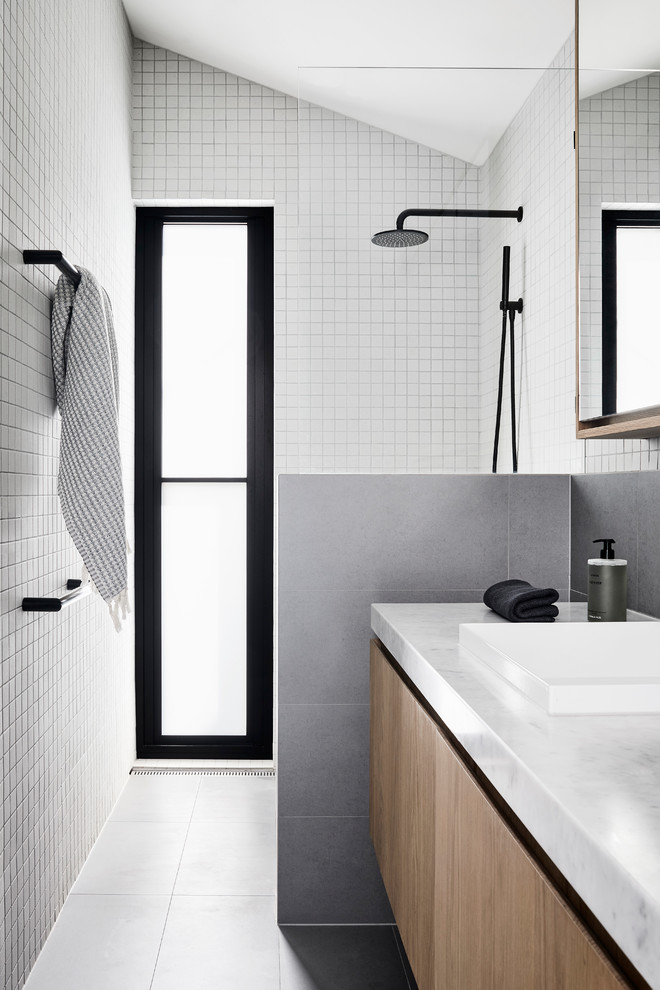 Источник вдохновения для домашнего уюта: маленькая ванная комната в современном стиле с светлыми деревянными фасадами, открытым душем, серой плиткой, белой плиткой, керамической плиткой, белыми стенами, полом из керамической плитки, накладной раковиной, мраморной столешницей, серым полом, открытым душем, белой столешницей, плоскими фасадами, душевой кабиной и окном для на участке и в саду