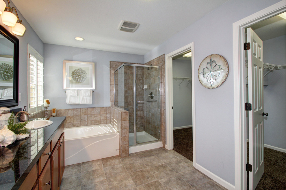 Bild på ett vintage badrum, med ett nedsänkt handfat, luckor med upphöjd panel, skåp i mellenmörkt trä, granitbänkskiva, ett fristående badkar, beige kakel och stenkakel