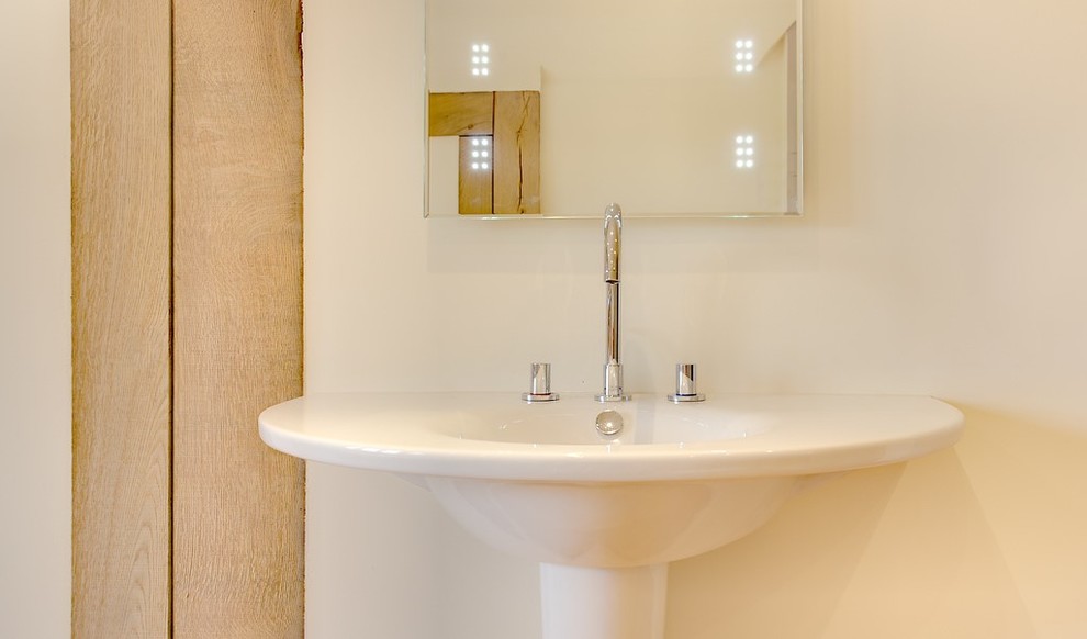 Idee per una stanza da bagno contemporanea con lavabo a colonna, pareti bianche e parquet chiaro