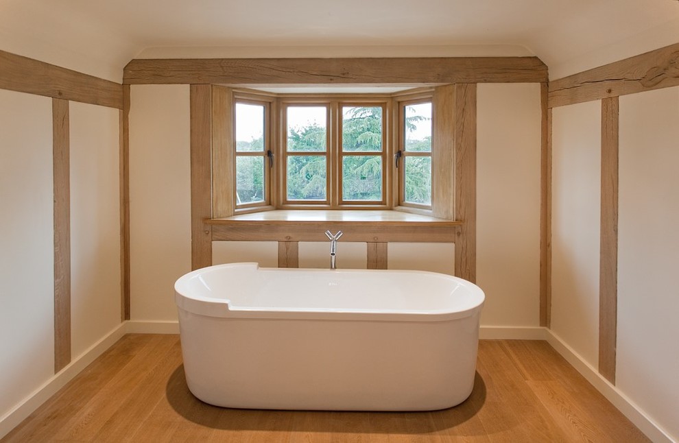 Inspiration for a contemporary ensuite bathroom in West Midlands with a console sink, a freestanding bath, white walls and light hardwood flooring.