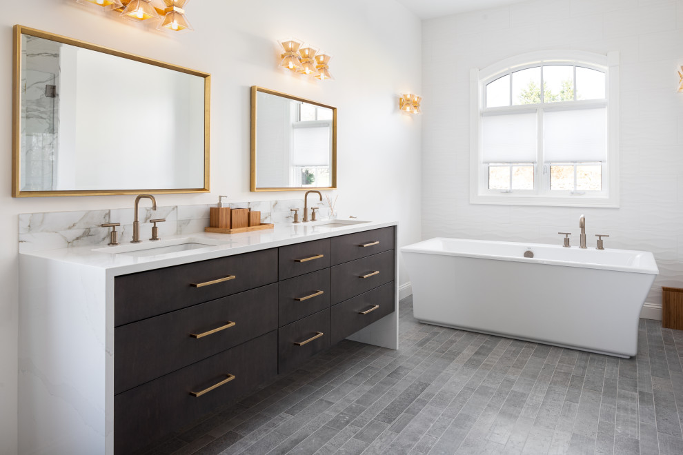 Design ideas for a contemporary ensuite bathroom with flat-panel cabinets, dark wood cabinets, a freestanding bath, a submerged sink, grey floors and white worktops.