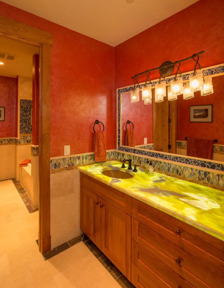 デンバーにある広い地中海スタイルのおしゃれなマスターバスルーム (アンダーカウンター洗面器、中間色木目調キャビネット、アルコーブ型浴槽、赤い壁、セラミックタイルの床、フラットパネル扉のキャビネット、クオーツストーンの洗面台) の写真