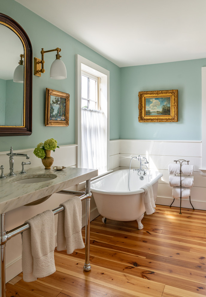 Mid-sized farmhouse white tile and ceramic tile light wood floor, single-sink and shiplap wall claw-foot bathtub photo in Boston with blue walls, a console sink, a freestanding vanity, marble countertops and white countertops