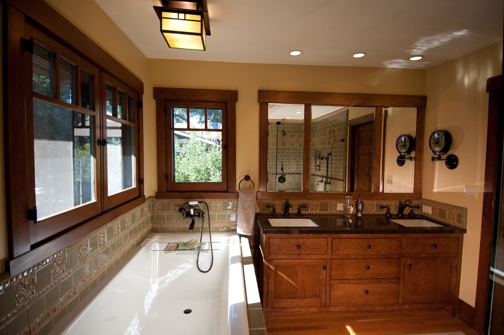 This is an example of a medium sized traditional ensuite bathroom in Los Angeles with a submerged sink, freestanding cabinets, medium wood cabinets, granite worktops, a built-in bath, a corner shower, a two-piece toilet, green tiles, ceramic tiles, yellow walls and medium hardwood flooring.