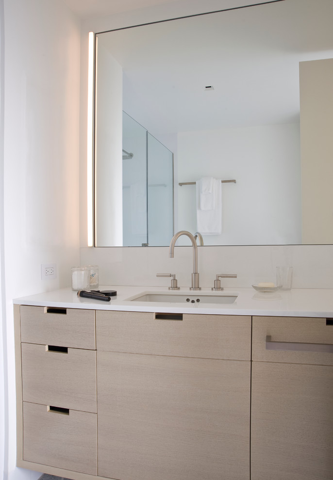 Medium sized contemporary ensuite bathroom in New York with a submerged sink, flat-panel cabinets, light wood cabinets, engineered stone worktops, an alcove shower, a one-piece toilet, white tiles, glass tiles, white walls and mosaic tile flooring.