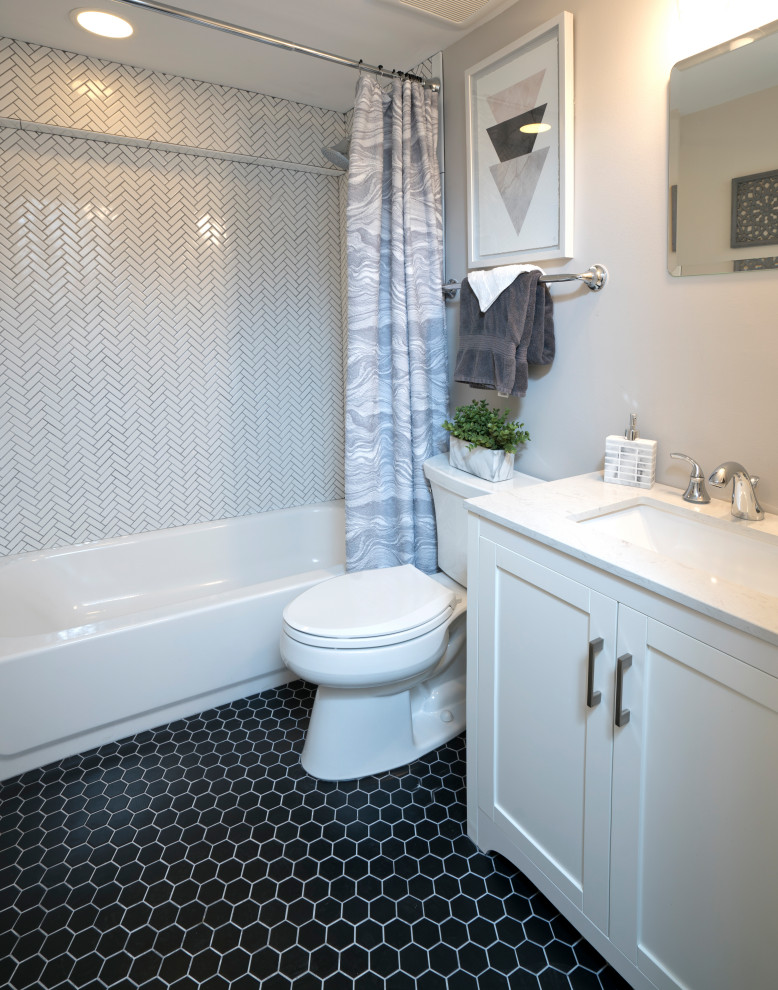 Foto på ett litet funkis vit badrum, med luckor med infälld panel, vita skåp, en toalettstol med separat cisternkåpa, vit kakel, vita väggar, klinkergolv i keramik, ett undermonterad handfat, bänkskiva i kvarts, svart golv, ett badkar i en alkov och en dusch/badkar-kombination
