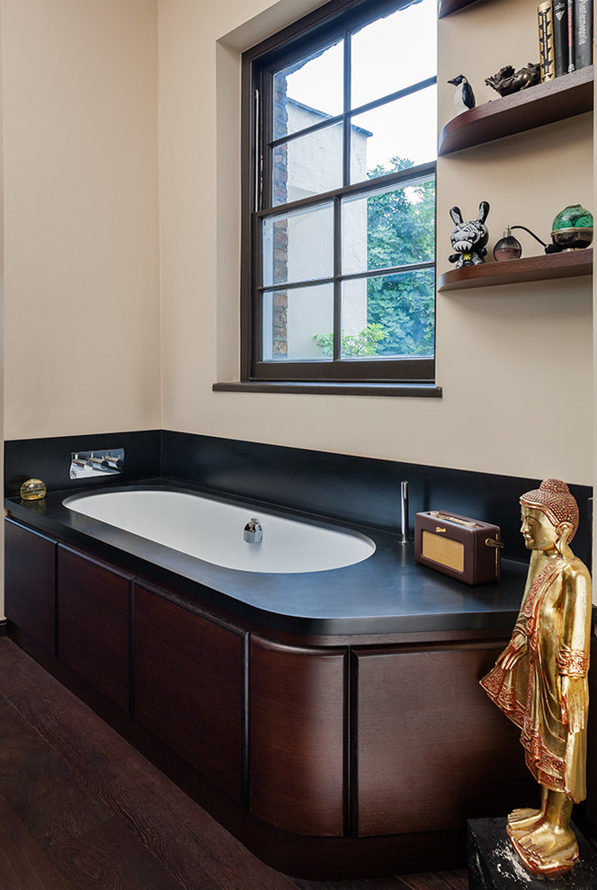 Example of a classic bathroom design in London with an undermount sink, open cabinets, dark wood cabinets, quartz countertops, an undermount tub and a wall-mount toilet